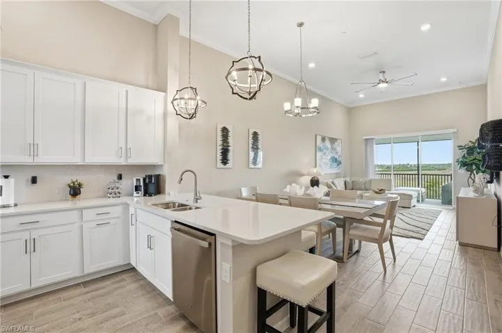 Kitchen with white cabinets, dishwasher, open floor plan, decorative light fixtures, and wood tiled floors