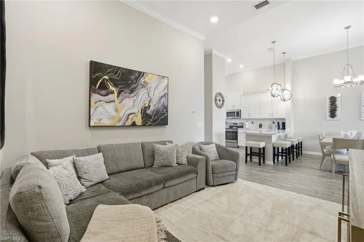 Living area with a chandelier, ornamental molding, recessed lighting, and light wood-type flooring