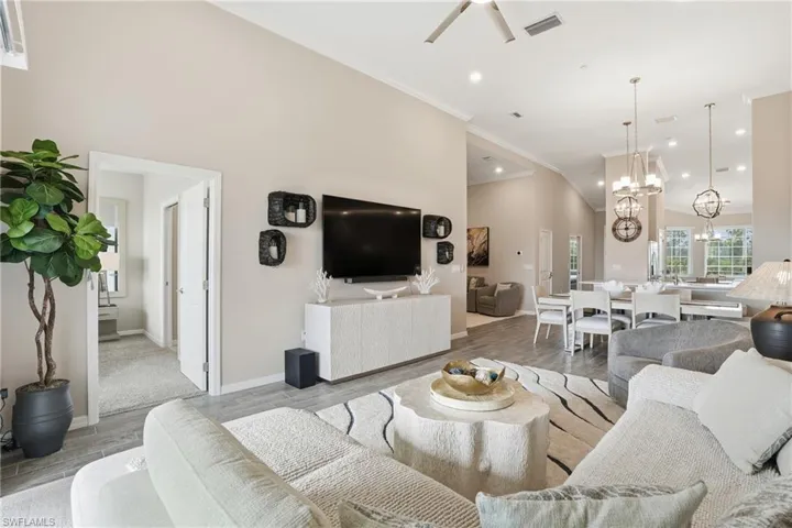 Living area featuring wood finish floors, crown molding, recessed lighting, and a chandelier