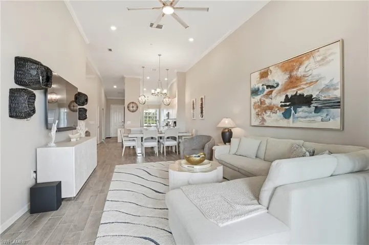 Living area featuring wood tiled floors, ornamental molding, recessed lighting, a chandelier, and a ceiling fan