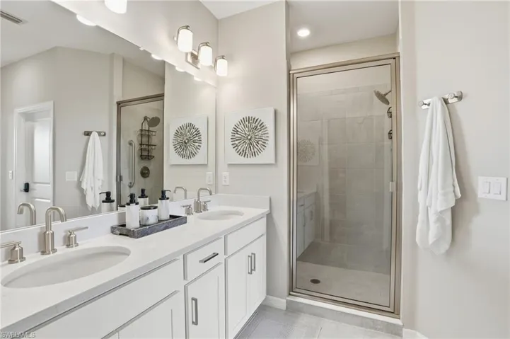 Full bathroom with double vanity, a shower stall, and light tile patterned floors