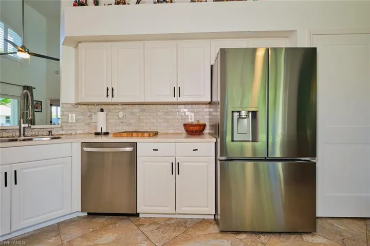 Kitchen featuring stainless steel appliances, a sink, tasteful backsplash, and light countertops