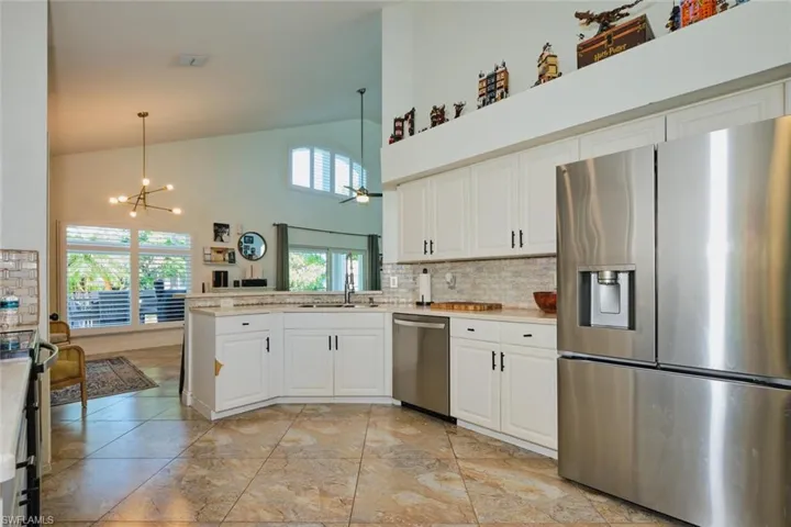 Kitchen featuring appliances with stainless steel finishes, a chandelier, white cabinetry, light countertops, and high vaulted ceiling