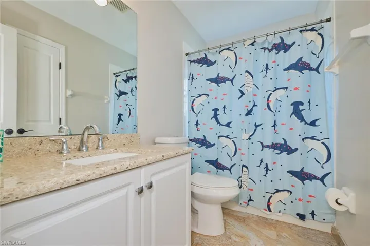 Bathroom featuring toilet, vanity, and curtained shower