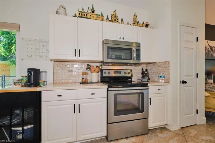 Kitchen featuring stainless steel appliances, light countertops, white cabinets, and tasteful backsplash