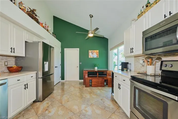 Kitchen with stainless steel appliances, high vaulted ceiling, light countertops, backsplash, and ceiling fan