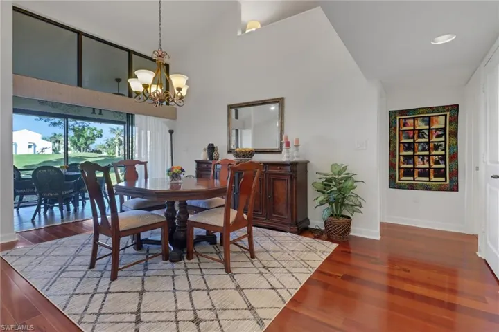 Dining area with an inviting chandelier, hardwood / wood-style floors, and a towering ceiling