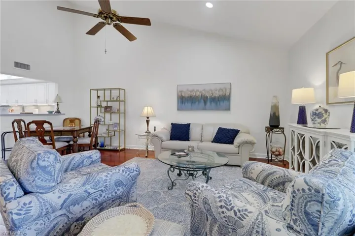 Living room with wood-type flooring, high vaulted ceiling, and ceiling fan
