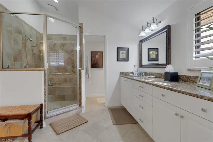 Bathroom with a shower with door, vanity, and lofted ceiling