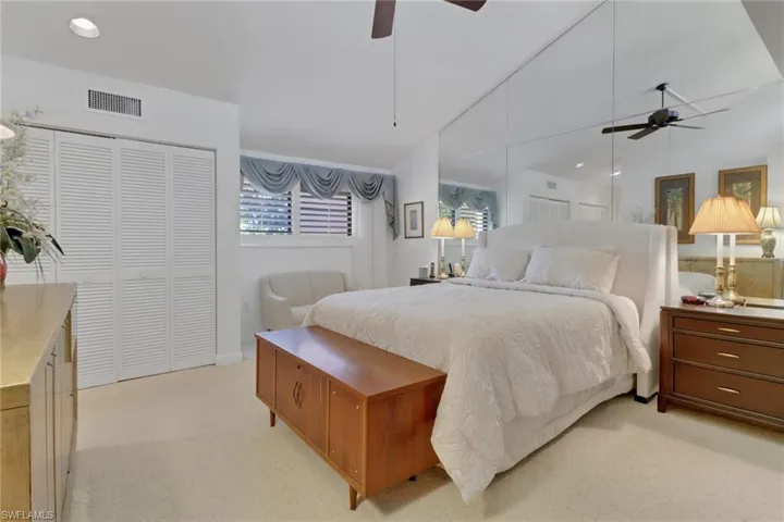 Carpeted bedroom featuring vaulted ceiling, ceiling fan, and a closet