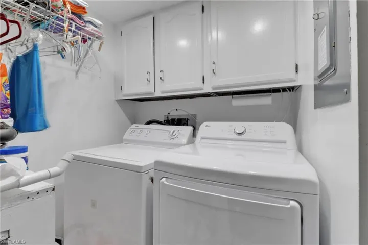 Laundry room featuring cabinets, electric panel, and washer and clothes dryer