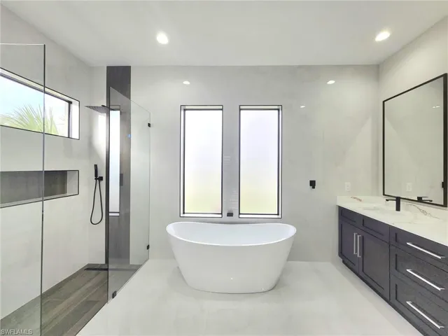 Bathroom featuring vanity, tile walls, and separate shower and tub