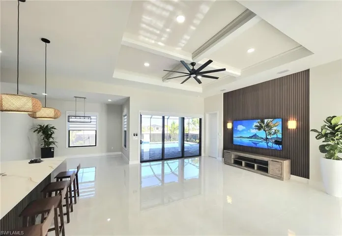Living room featuring coffered ceiling, ceiling fan, built in desk, and beamed ceiling