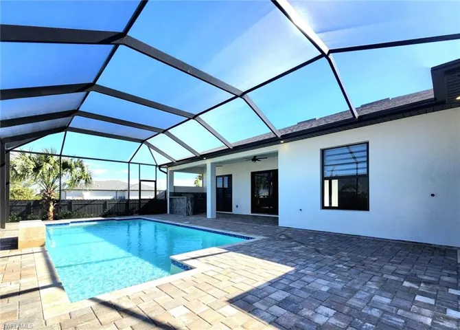 View of swimming pool featuring ceiling fan, glass enclosure, and a patio area