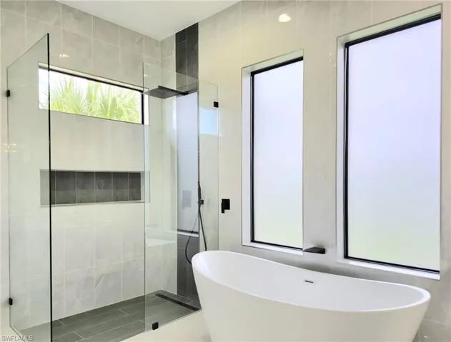 Bathroom with separate shower and tub and tile walls
