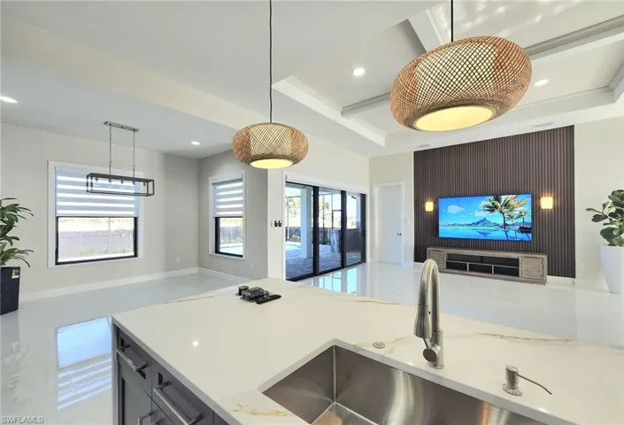 Kitchen featuring beamed ceiling, sink, hanging light fixtures, coffered ceiling, and light stone counters