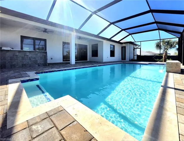 View of swimming pool with a patio area, ceiling fan, and glass enclosure