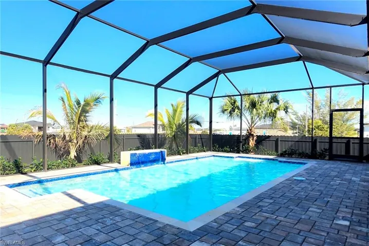 View of pool with pool water feature, a patio, and glass enclosure