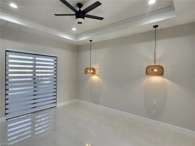 Empty room featuring a raised ceiling and ceiling fan