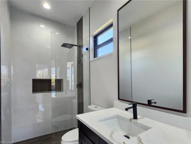 Bathroom featuring vanity, tiled shower, and toilet