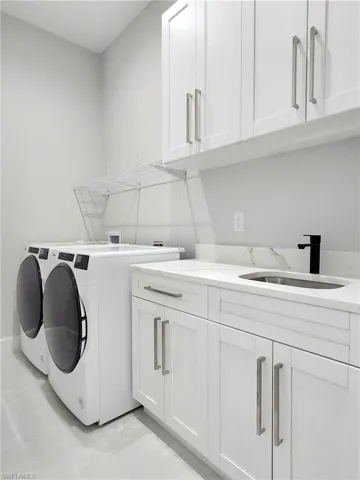 Washroom with cabinets, sink, and washing machine and dryer