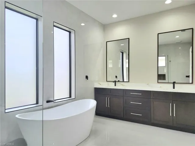 Bathroom with a washtub, vanity, and plenty of natural light