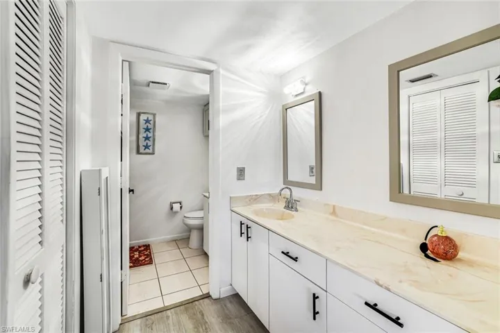Bathroom featuring a closet, vanity, and light wood-style flooring