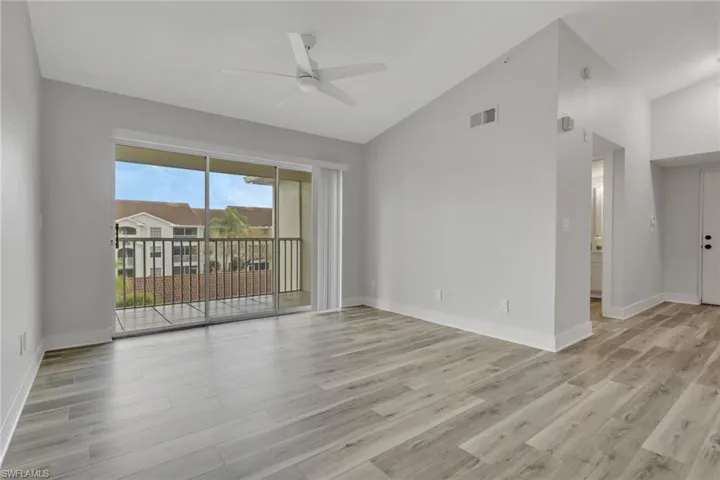 Empty room with vaulted ceiling, ceiling fan, and light wood-style floors