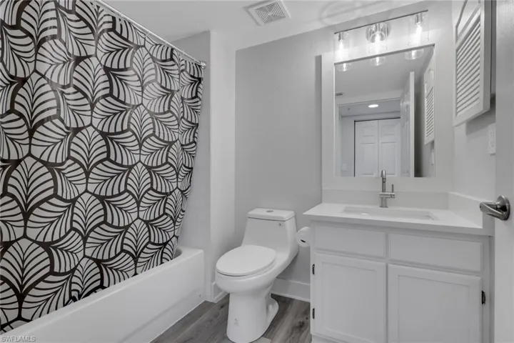 Guest bathroom featuring vanity, shower / tub combo, and light wood-style flooring