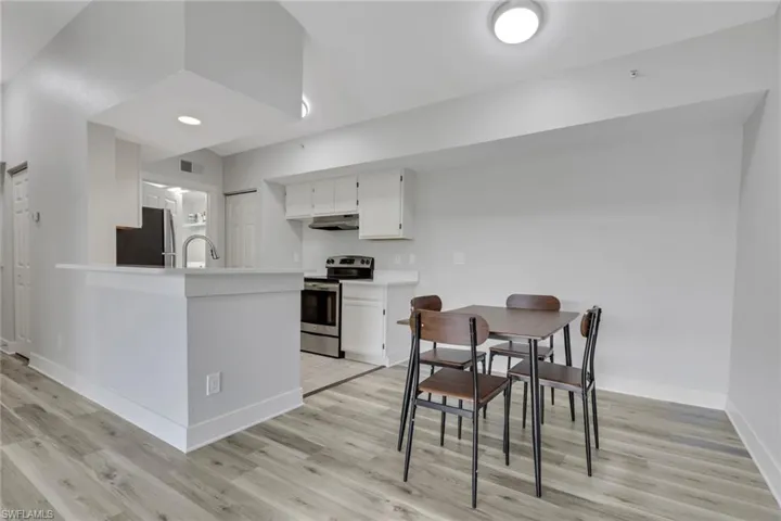 Kitchen with light countertops, stainless steel appliances, white cabinetry, and light wood finished floors
