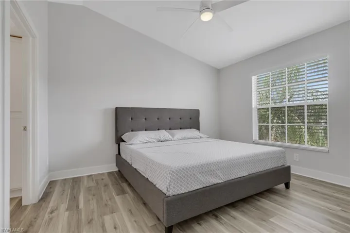 Primary bedroom with lofted ceiling, light wood-style flooring, and ceiling fan