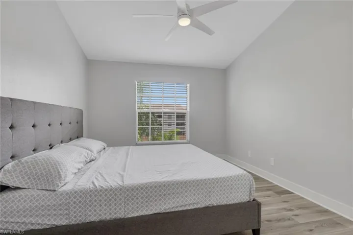 Primary bedroom with light wood-style flooring, ceiling fan, and lofted ceiling