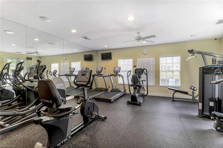 Exercise room with a ceiling fan, a textured ceiling, and recessed lighting