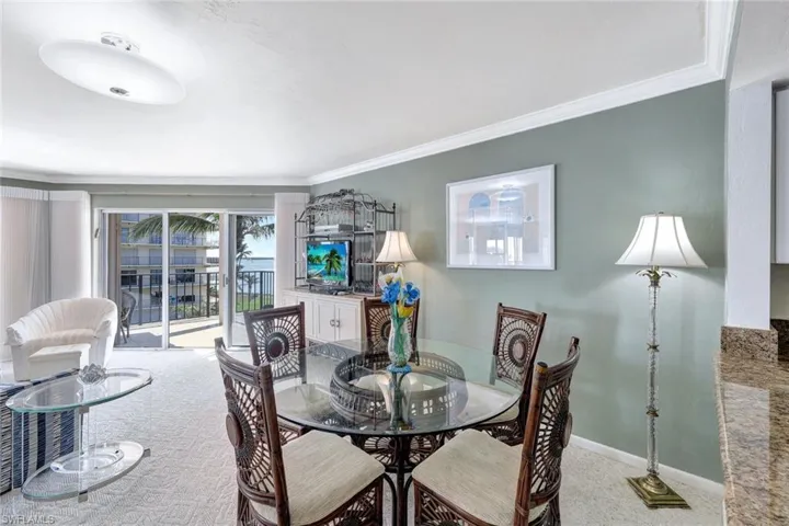 Dining room with ornamental molding and light carpet
