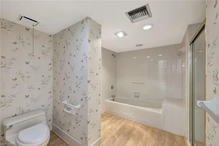 Bathroom featuring separate shower and tub, toilet, and hardwood / wood-style flooring