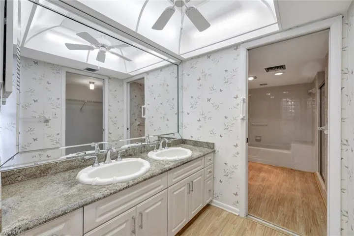 Bathroom with vanity, hardwood / wood-style floors, ceiling fan, and shower / bath combination with glass door