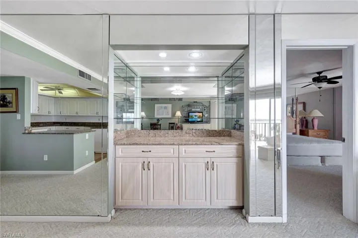 Kitchen with ceiling fan, light colored carpet, and light stone countertops