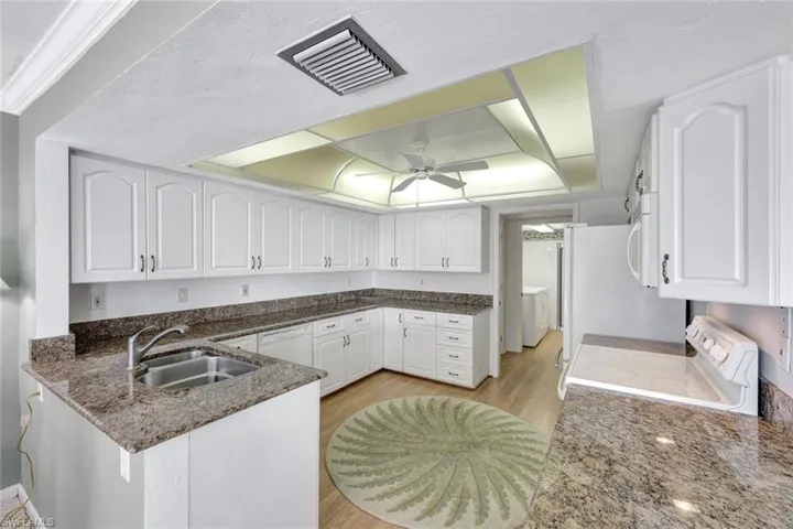 Kitchen featuring sink, white appliances, white cabinets, and kitchen peninsula