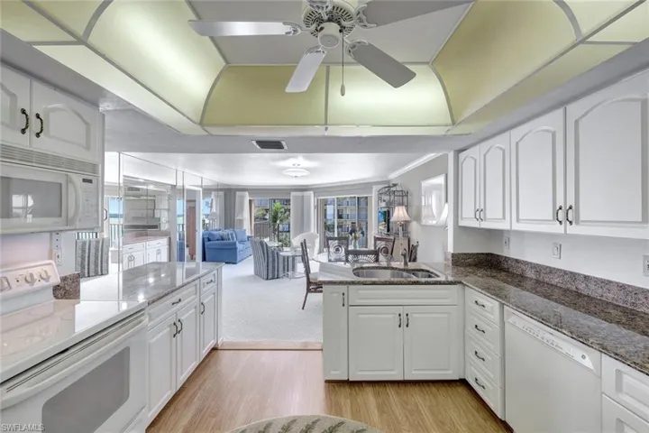 Kitchen with white appliances, white cabinets, and sink
