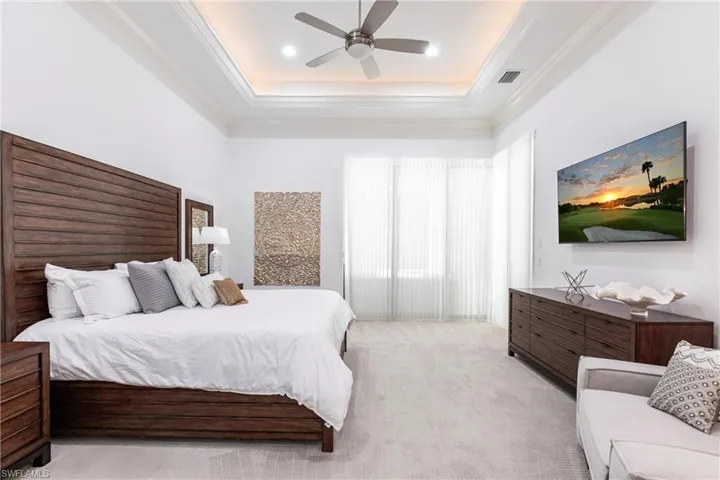 Bedroom featuring visible vents, light colored carpet, a ceiling fan, and ornamental molding