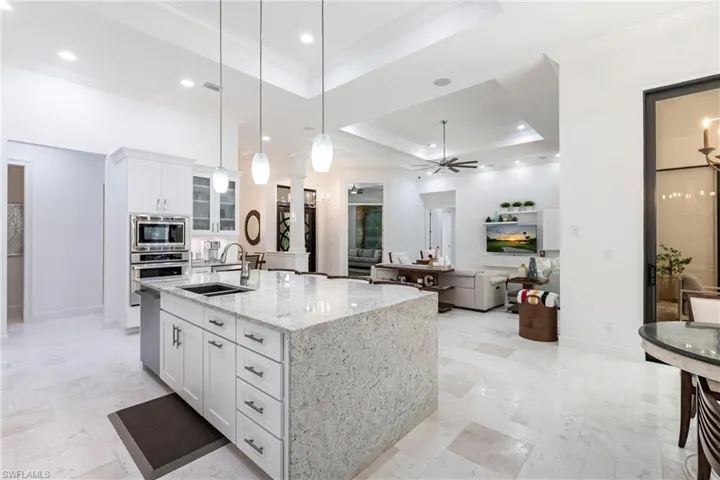 Kitchen with crown molding, stainless steel appliances, white cabinetry, a raised ceiling, and a sink