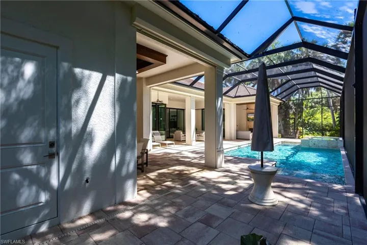 View of pool featuring glass enclosure, a patio, and a pool with connected hot tub