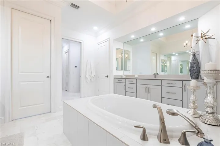 Full bathroom with visible vents, a notable chandelier, crown molding, a bath, and vanity