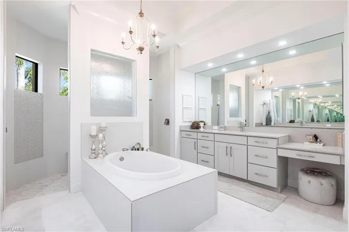 Bathroom featuring vanity, an inviting chandelier, recessed lighting, a tile shower, and a garden tub