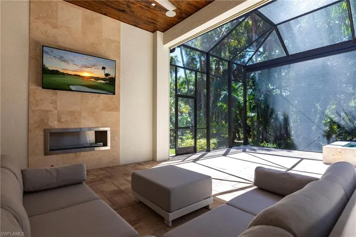 Living room with wooden ceiling, a tile fireplace, a sunroom, and stone tile flooring