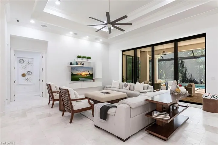 Living room featuring recessed lighting, a tray ceiling, ceiling fan, and ornamental molding