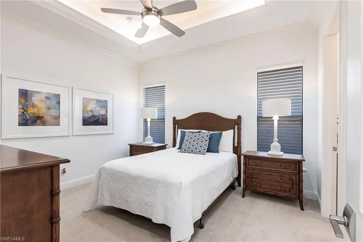 Bedroom featuring a tray ceiling, light colored carpet, baseboards, and ornamental molding