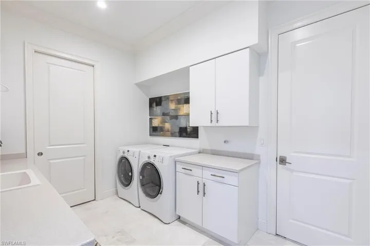Washroom featuring washer and dryer, cabinet space, crown molding, and a sink