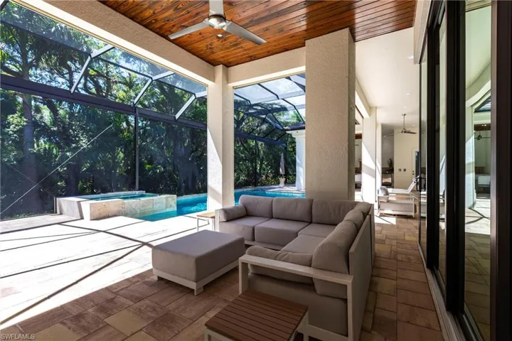 View of patio / terrace featuring ceiling fan, glass enclosure, a pool with connected hot tub, and an outdoor hangout area