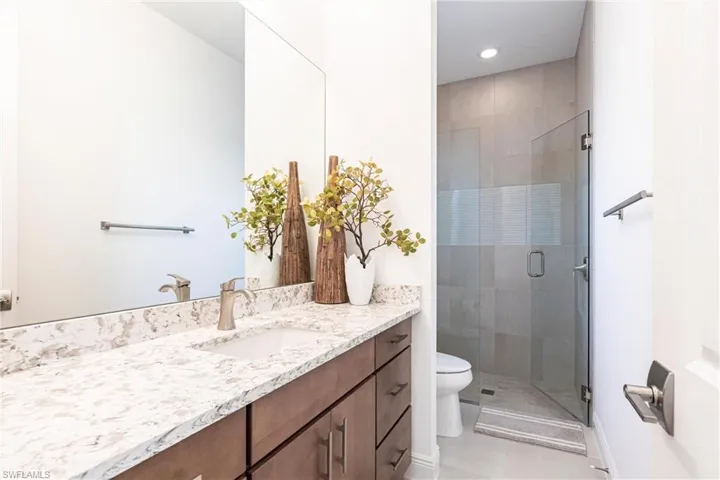 Bathroom featuring tile patterned flooring, toilet, recessed lighting, a stall shower, and vanity